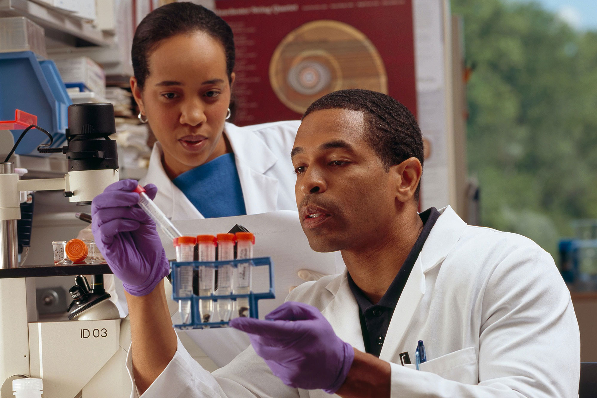 black woman and man in lab coats looking at test samples in lab