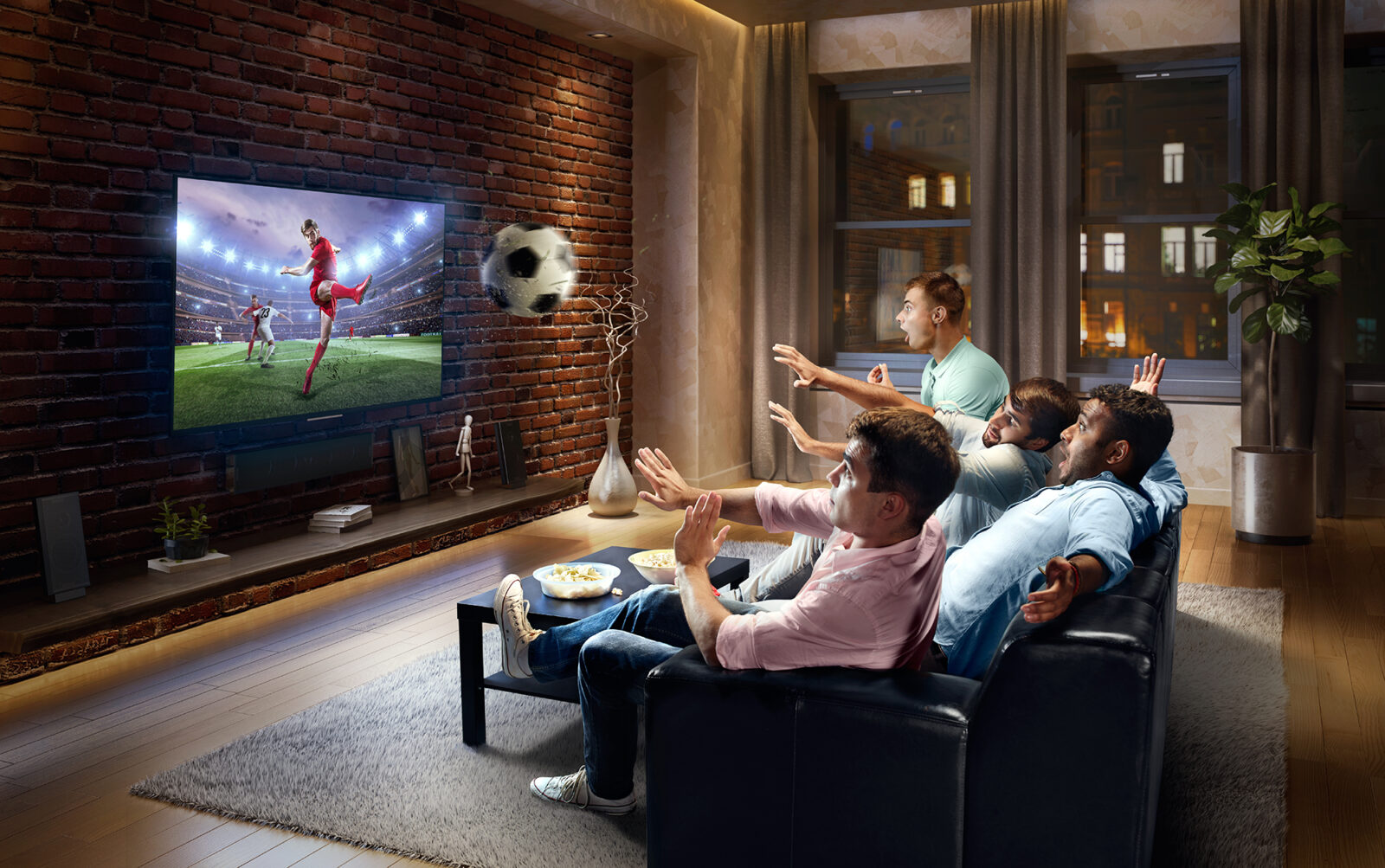 people on couch watching tv with soccer ball coming out of screen